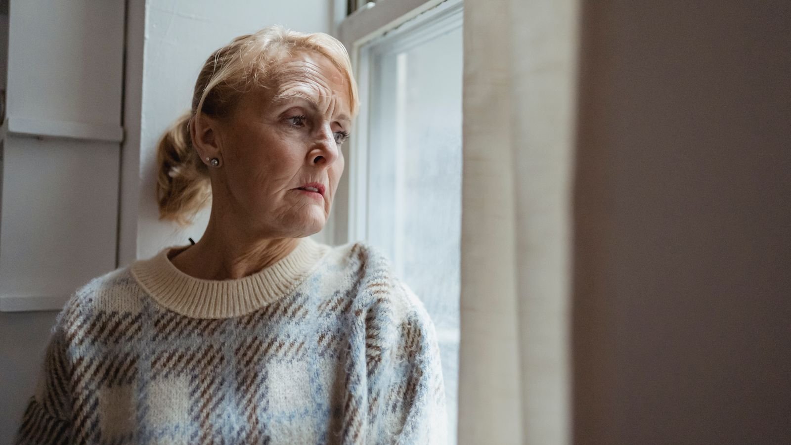 Midlife woman looking out of a window in soft natural light