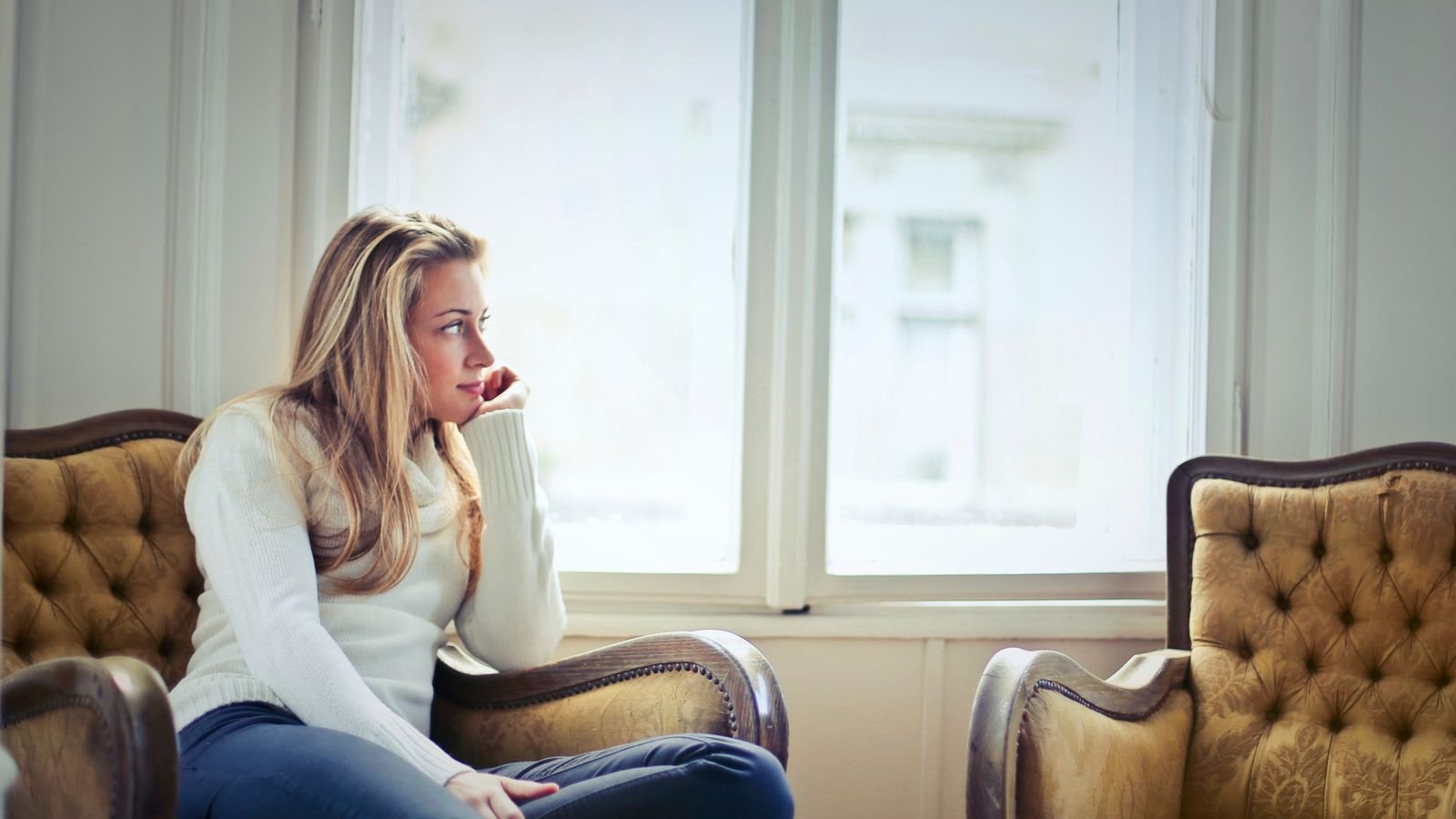 Woman sitting calmly in an armchair by a sunlit window